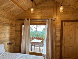 a bedroom in a log cabin with a bed and a window at Coorg Jungle Mist in Madikeri