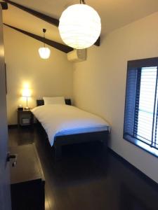 a bedroom with a white bed and a window at Maeniiya Machiya Inn in Kyoto