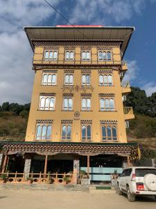 a tall yellow building with a roof at White Dragon Hotel in Punākha
