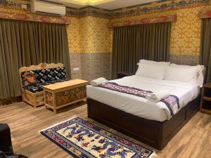 a bedroom with a large bed and a chair at White Dragon Hotel in Punākha