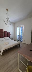 a white bedroom with a large bed and a table at ECO-HOUSE DA FRANCO in Civitanova Marche