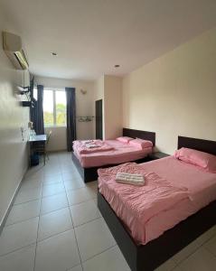 una camera d'albergo con due letti e una scrivania di Intanova Hotel a Teluk Intan