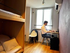 a man sitting at a desk in a dorm room at En Hostel & Bar in Kochi