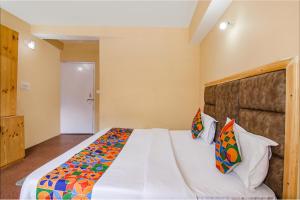 a bedroom with a large white bed with colorful pillows at FabHotel Nirvana Deluxe in Manāli