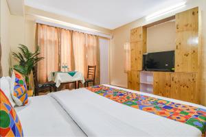 1 dormitorio con 1 cama, TV y mesa en FabHotel Nirvana Deluxe en Manāli