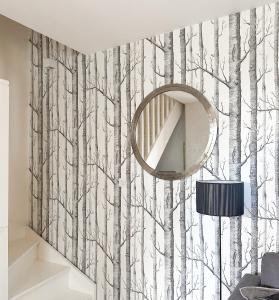 a room with a mirror and trees wallpaper at Le cottage de David in Pierrefonds