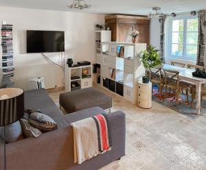 uma sala de estar com um sofá e uma sala de jantar em Le cottage de David em Pierrefonds