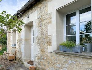 uma janela de uma casa de pedra com vasos de plantas sobre ela em Le cottage de David em Pierrefonds