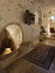 a stone room with a tv and a rug at Peruna Cave in Goreme