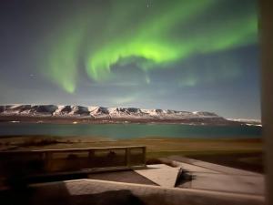 阿克雷里的住宿－Hotel Natur Akureyri，享有白雪覆盖的高山上方的极光景色