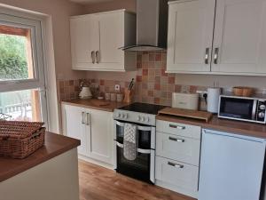 a kitchen with white cabinets and a stove top oven at Woodpeckers - Alresford Essex in Alresford