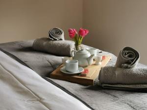 a tray with cups and saucers and flowers on a bed at Woodpeckers - Alresford Essex in Alresford