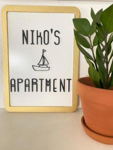 ein Schild, das Nizos-Wohnung neben einer Pflanze liest in der Unterkunft Nikos apartment in Malia