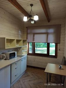 a kitchen with white cabinets and a large window at Явір Резорт in Starychi