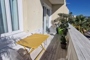 un tavolo giallo e sedie sul balcone di Magnifique 3 pièces/terrasse/promenade des Anglais a Nizza