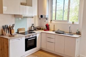 uma cozinha com armários brancos e um forno com placa de fogão em Magnifique 3 pièces/terrasse/promenade des Anglais em Nice