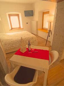 Habitación con cama y mesa con copa de vino en Casa Colibrì - Welcome to a Mountain Dream en Forni di Sopra