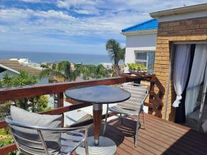 een tafel en stoelen op een balkon met uitzicht op de oceaan bij Captains View in Jeffreys Bay