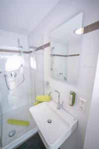 a white bathroom with a sink and a shower at CityApartements FN2-FN4 KLIMATISIERT in Friedrichshafen