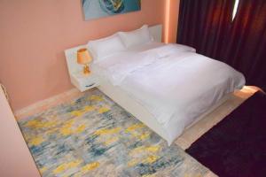 a bedroom with a white bed and a rug at EnZ lovely 2 bedroom Apartment Milimani Nakuru in Nakuru