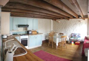 uma cozinha com armários azuis e uma mesa e uma mesa; em The Old Barn em Barry