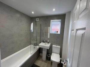 a bathroom with a sink and a toilet and a shower at 3 Bedroom New House with Wi-Fi Sleep 5 By Home Away From Home - A in Newcastle under Lyme +30 photos