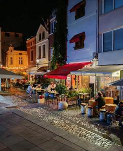 a group of people sitting at tables in a street at night at Studio Maria- Prime Location in Kapana District in Plovdiv