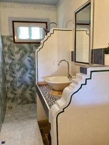 uma casa de banho com um lavatório num balcão com um espelho em La Reine Creole em La Gaulette