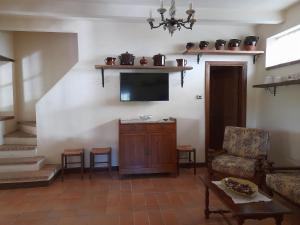uma sala de estar com uma televisão e uma cadeira em Agriturismo del Frontino - Ca' Benvenuto em Acqualagna