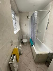 a bathroom with a toilet and a tub and a sink at The Leavesley in Blackpool