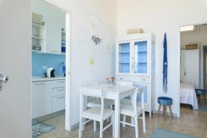 une cuisine avec des placards blancs et une table et des chaises blanches dans l'établissement Casa Helios, à Villanova di Ostuni
