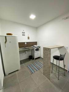 a kitchen with a white refrigerator and a table at Suite Vargem Grande 2 - praia, cachoeira e trilhas in Rio de Janeiro