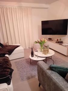 a living room with a couch and a table with a tv at Sailors' Park Villa Zephir in Nieuwpoort