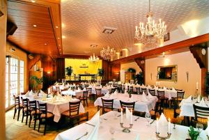 een restaurant met witte tafels en stoelen en een kroonluchter bij Hotel und Restaurant Adler 
