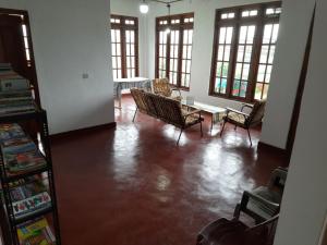 a living room with chairs and a table and windows at Green Villa in Nuwara Eliya