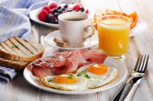 un plato de desayuno con huevos y tostadas y una taza de café en Hotel Rooms DHA en Karachi