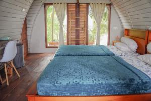 Schlafzimmer mit einem großen Bett mit blauer Decke in der Unterkunft Momos Surf Shack in Salul