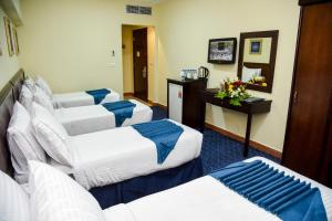a hotel room with four beds and a desk at Plaza Inn Ohud Hotel in Al Madinah +8 photos
