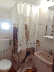 La salle de bains est pourvue d'un rideau de douche, de toilettes et d'un lavabo. dans l'établissement Samos Rooms, à Pythagoreio