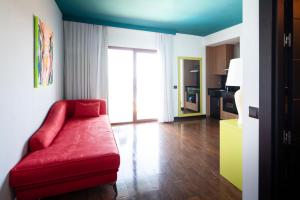 a living room with a red couch and a kitchen at Hotel Ritual Torremolinos- Adults Only in Torremolinos