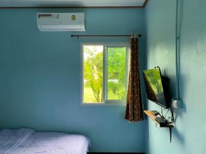 een blauwe kamer met een bed en een raam bij Sappermpool Homestay Buengkhonglong 