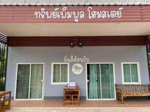 a building with a bench and a sign on it at Sappermpool Homestay Buengkhonglong 
