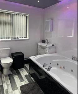 a white bathroom with a tub and a toilet at SEA VIEW Apartment Large Balcony Whirlpool Bath 2 Bedrooms SKY GLASS TV in Bridlington