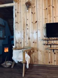 a room with a wooden wall with a table and a fireplace at Nomad Lodge Zminica in Žabljak