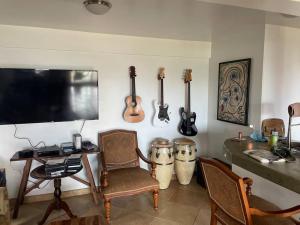 a living room with a tv and some instruments on the wall at Helehele Hale in Hana