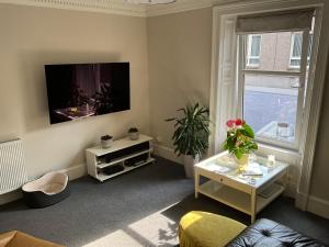 a living room with a tv on the wall at The Old Post Office Double Room (town centre) in Carnoustie