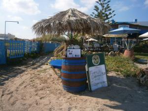 a barrel with a sign and a straw umbrella at Blue Sky Taverna Apartments Kiki in Adelianos Kampos