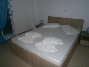 a bed with white sheets and towels on it at Blue Sky Taverna Apartments Kiki in Adelianos Kampos