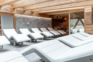 Habitación con sillas blancas y pared de piedra. en Hôtel Alpina & SPA en Les Gets