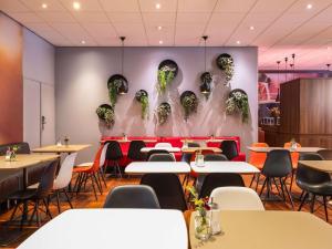 a restaurant with tables and chairs and a wall with faces at ibis Gent Centrum Opera in Ghent